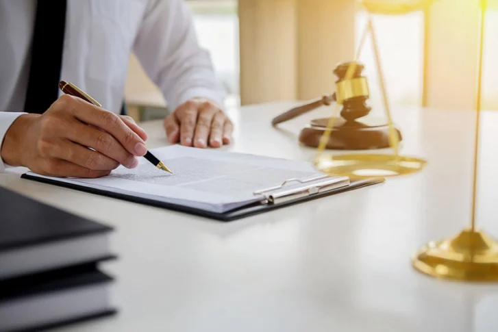 avocat ou notaire signant un document avec un marteau de justice sur le bureau